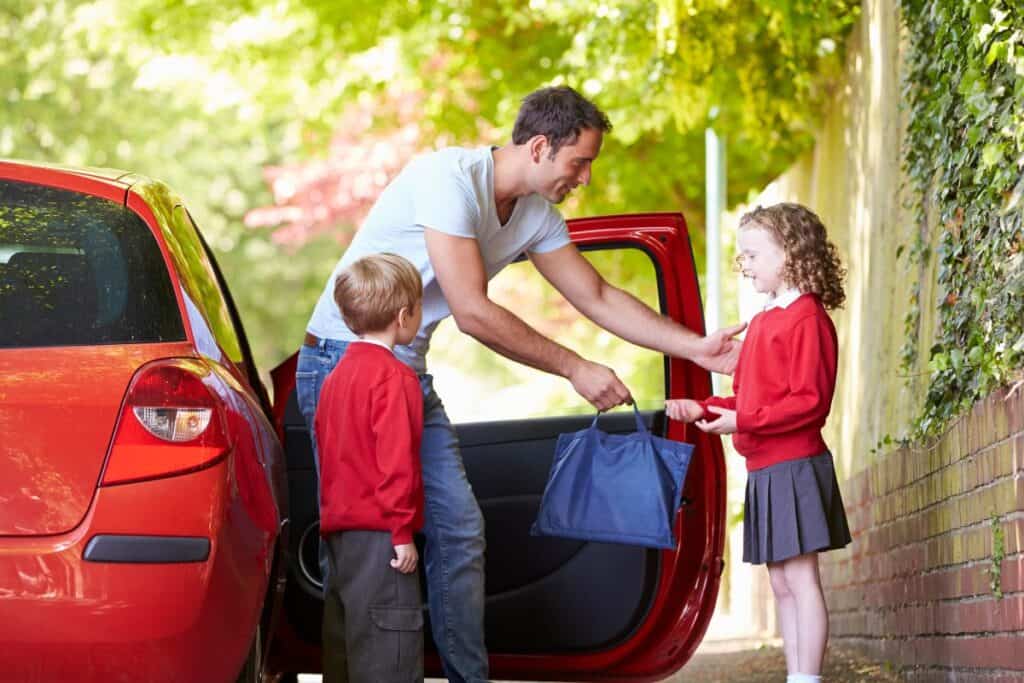 Parent helping children out of a car on the school run to show everyday family travel costs
